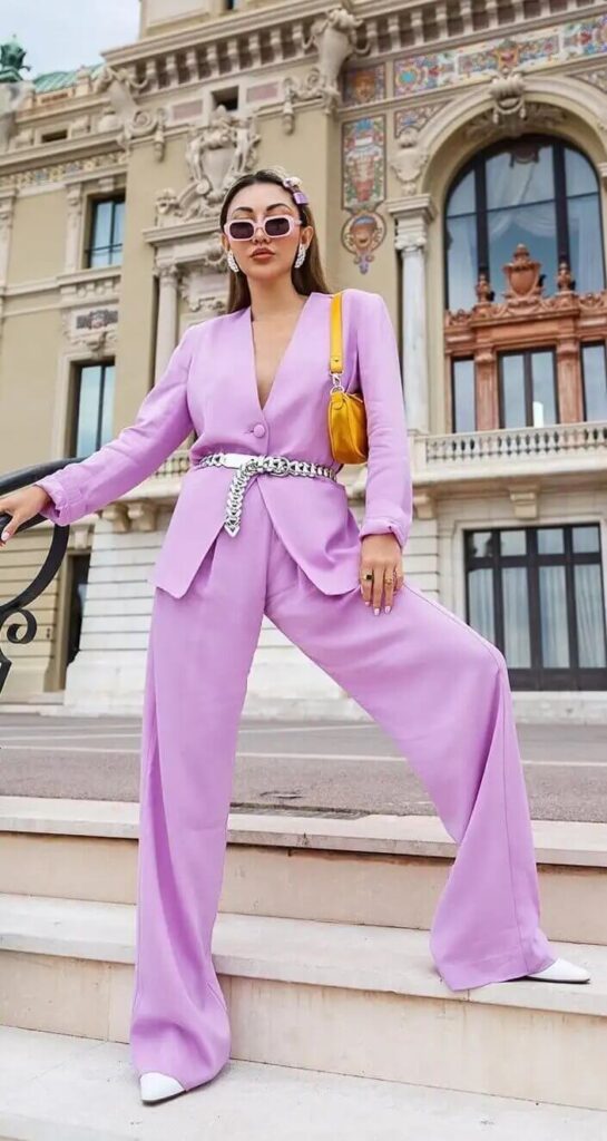 Girl in a lavender pantsuit posing on some stairs in the street